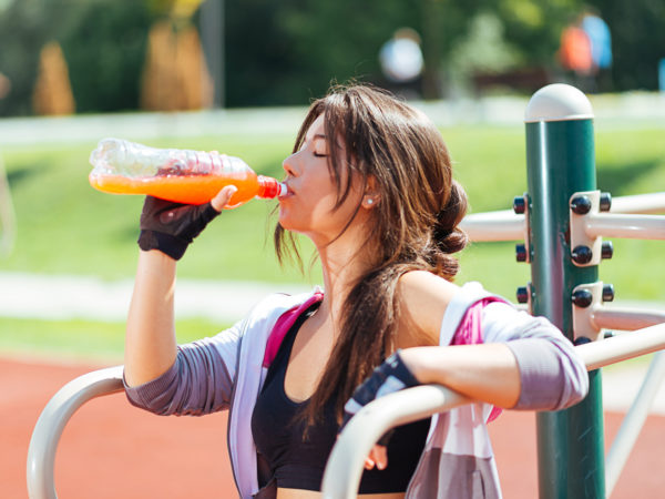 Young woman exercising and resting and drinking energy drink outdoors on sunny summer day in training outfit and feeling healthy and fit. Image taken with Nikon D800 and professional lens, developed from RAW in XXXL size