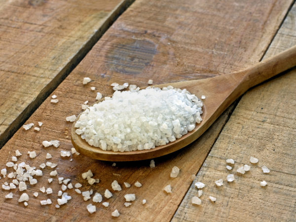 Salt in spoon on a wooden table - still life
