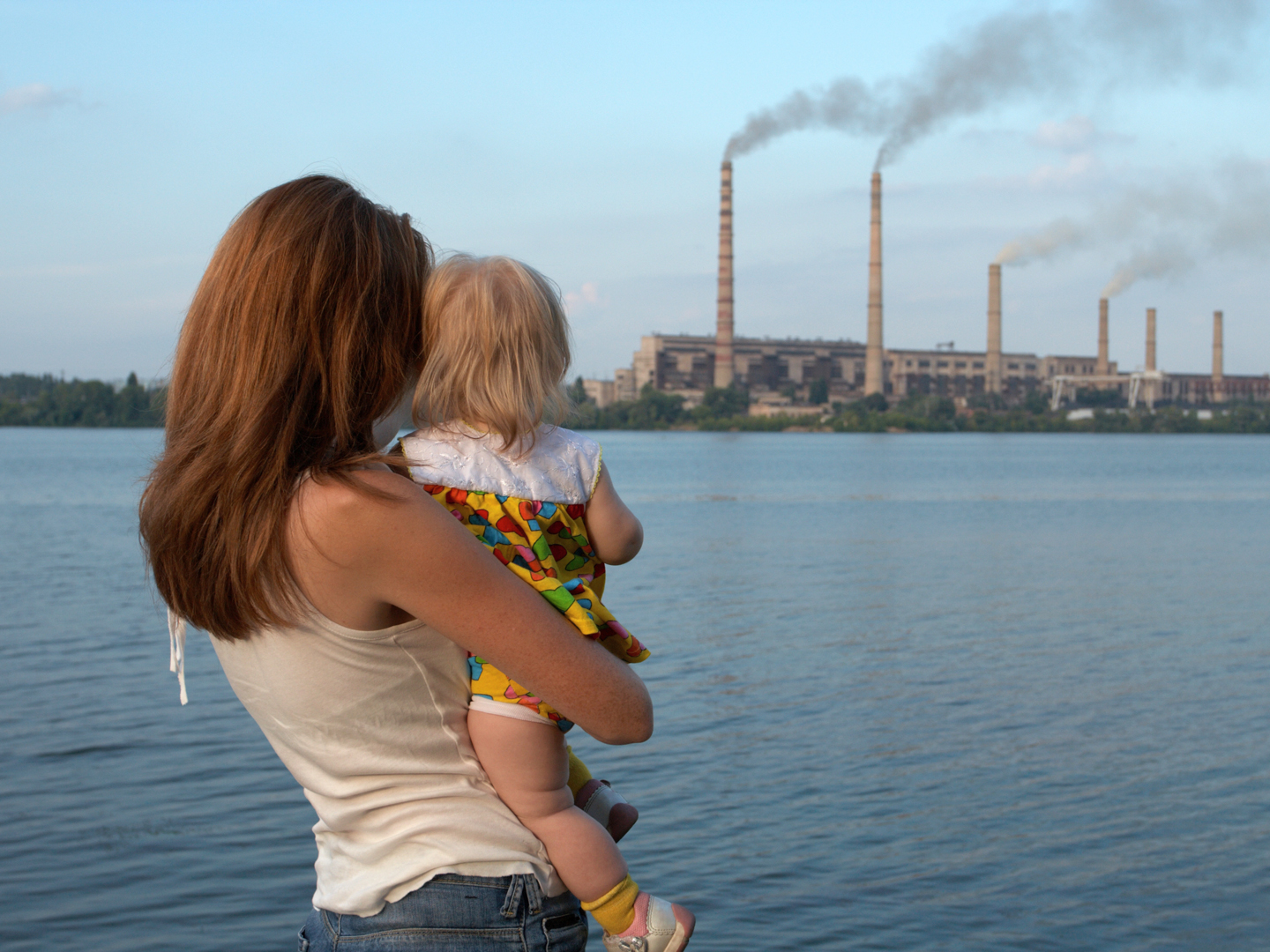 Young mother with her kids are looking at the chimney-stalks polluting an air