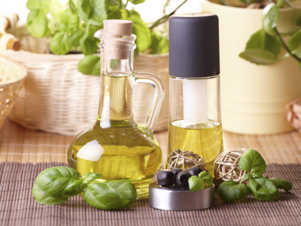 Two bottles with olive oil and grape seed oil with decoration of fresh basil and olives