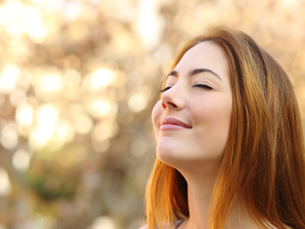 Portrait of a beautiful woman doing breath exercises with an autumn unfocused background