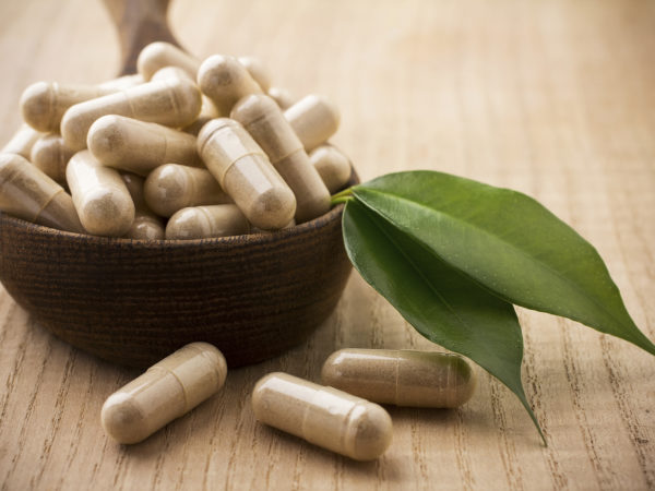 &quot;Alternative medicine tablets on a wooden spoon, green leaf.&quot;