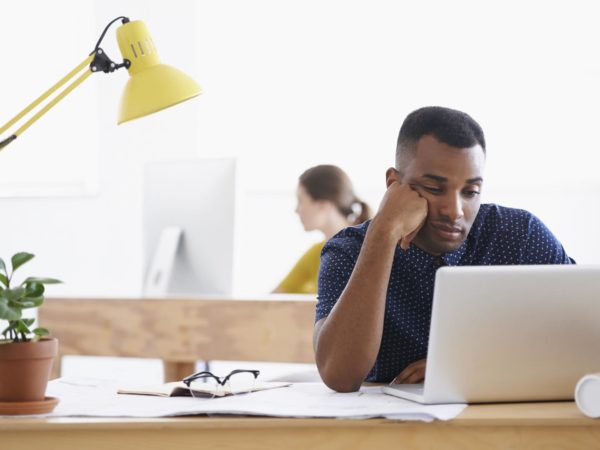 An ethnic businessman looking bored and tired as he sits behind his desk