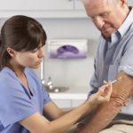 Doctor Giving Male Patient Injection In Hospital Room