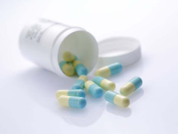 green-and-yellow capsules spilling from a prescription medicine bottle across the corner of a prescription ; shot with very shallow depth of field ,