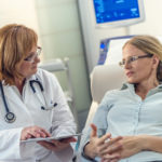 Patient on the bed telling her doctor about the problems she is having while the doctor is listening.