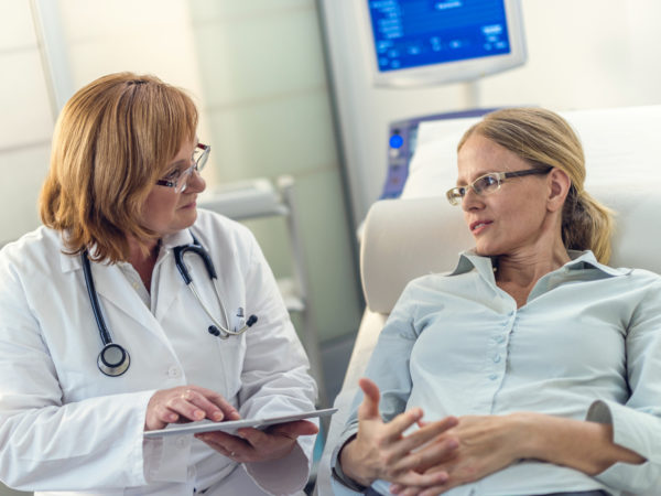 Patient on the bed telling her doctor about the problems she is having while the doctor is listening.