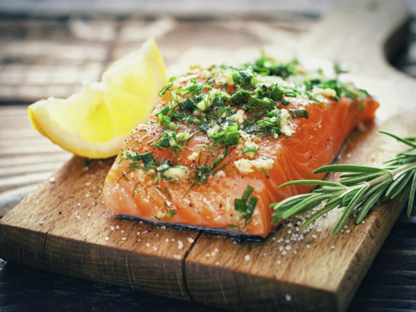 Raw salmon on a cutting board with fresh spices