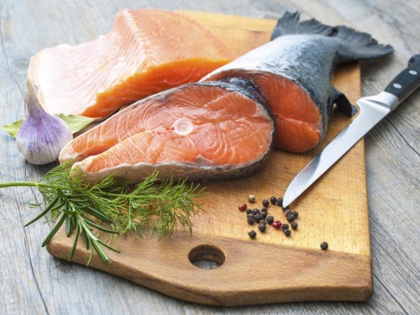 Raw salmon fish steaks with fresh herbs on cutting board