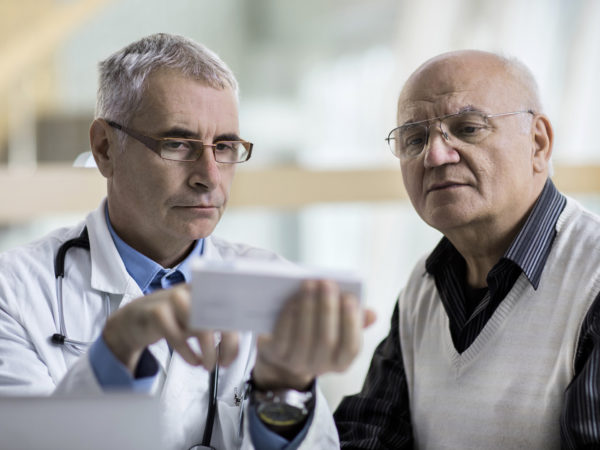 Mature doctor giving an advice to a senior man related to prescription medicine.