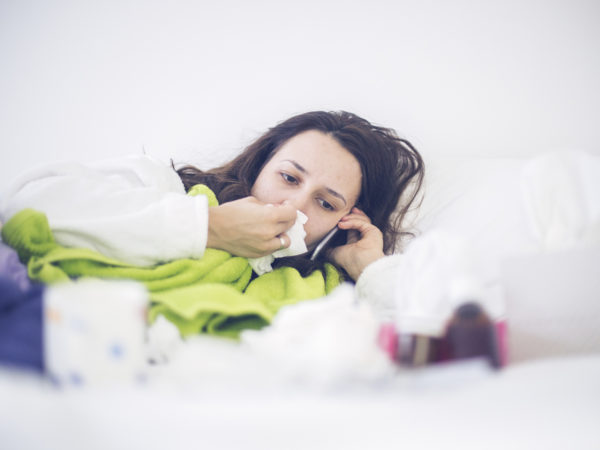 Sick woman calling doctor ,wiping nose with handkerchief