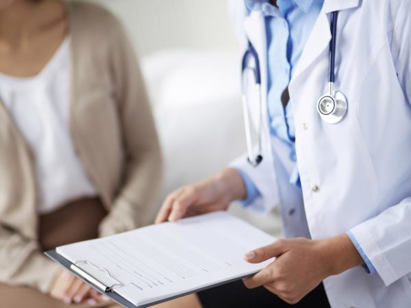 Female doctor holding application form while consulting patient