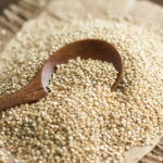 Pile of White Quinoa with a spoon on a wooden table