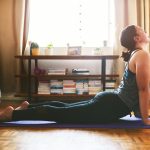 Cropped shot of an attractive young woman sitting and holding a cobra pose while doing yoga in her home