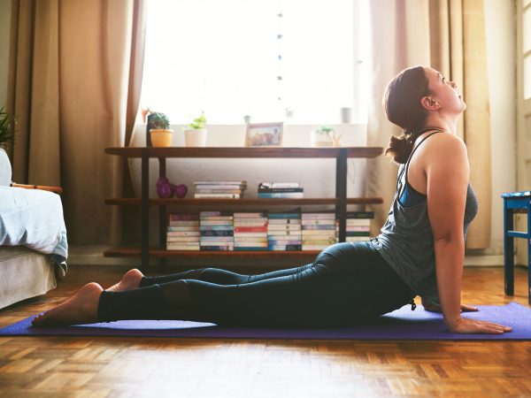 Cropped shot of an attractive young woman sitting and holding a cobra pose while doing yoga in her home