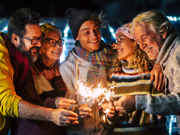 Caucasian happy family enjoy and celebrate by night with fire sparkler all together having fun - christmas and new year eve celebration for group of cheerful people mixed ages and generations