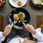 Close-up on a woman eating salmon for dinner at a restaurant - food and drink concepts