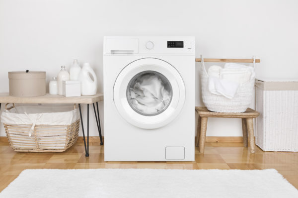 Domestic room interior with modern washing machine and laundry baskets