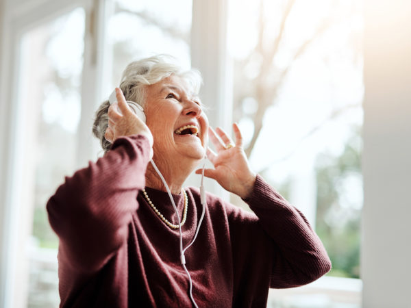Shot of happy senior woman listening to music with headphones at a retirement home