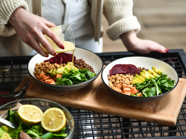 Female Preparing Aesthetically Pleasing Salad Bowls Adding Dressing on Top To Tie Flavors Together