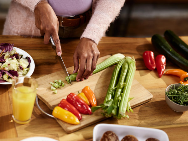 Close up of unrecognizable black woman cutting celery in the kitchen.
